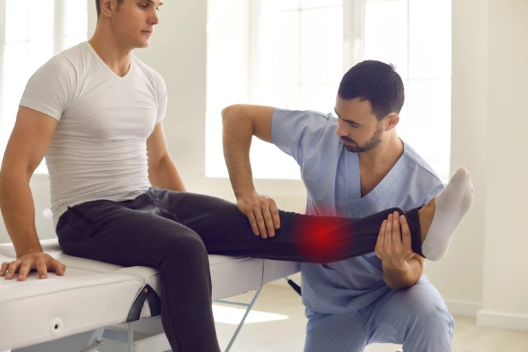 Physiotherapist massaging patient with leg injury